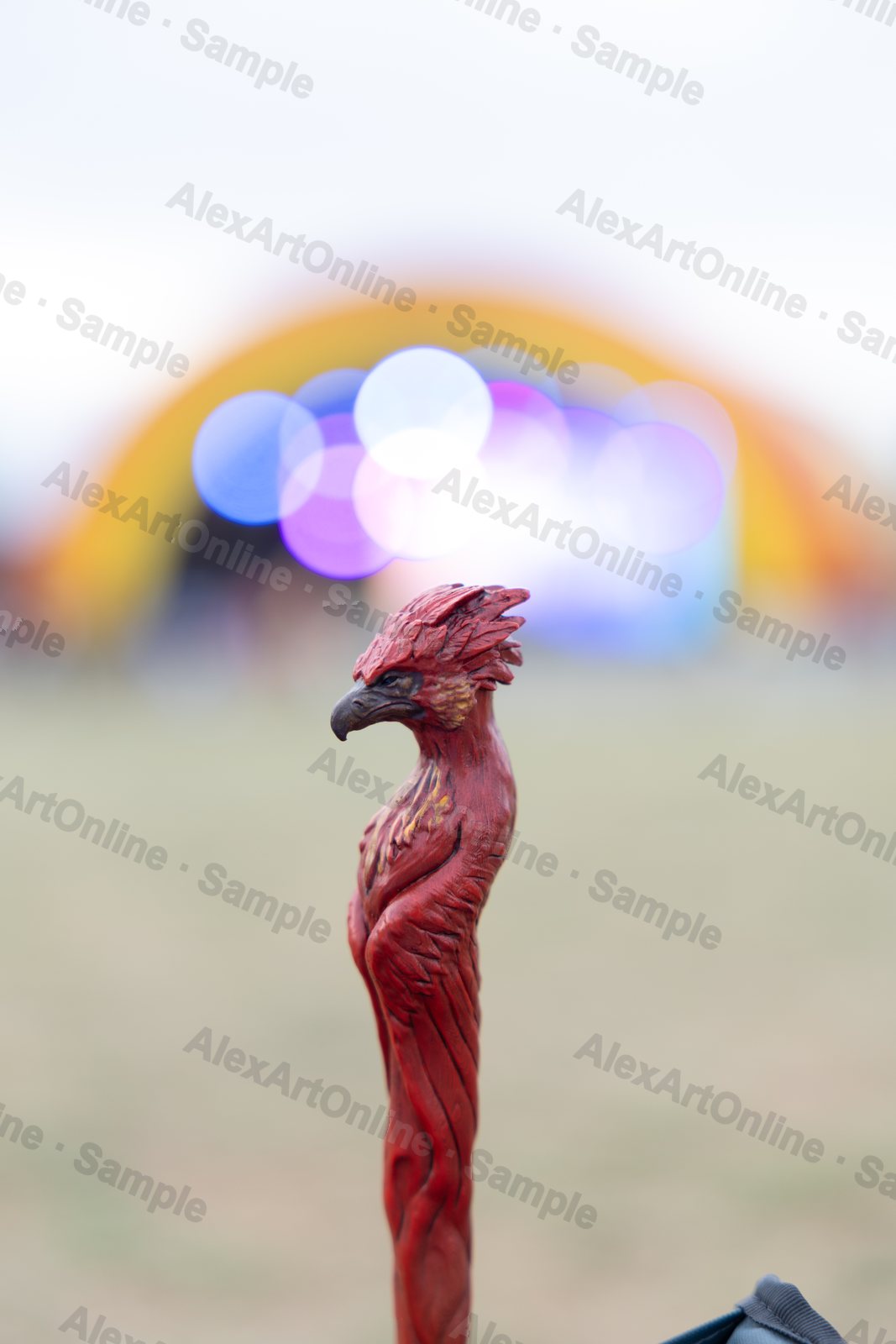 A carved wooden bird-head walking cane against colourful festival bokeh