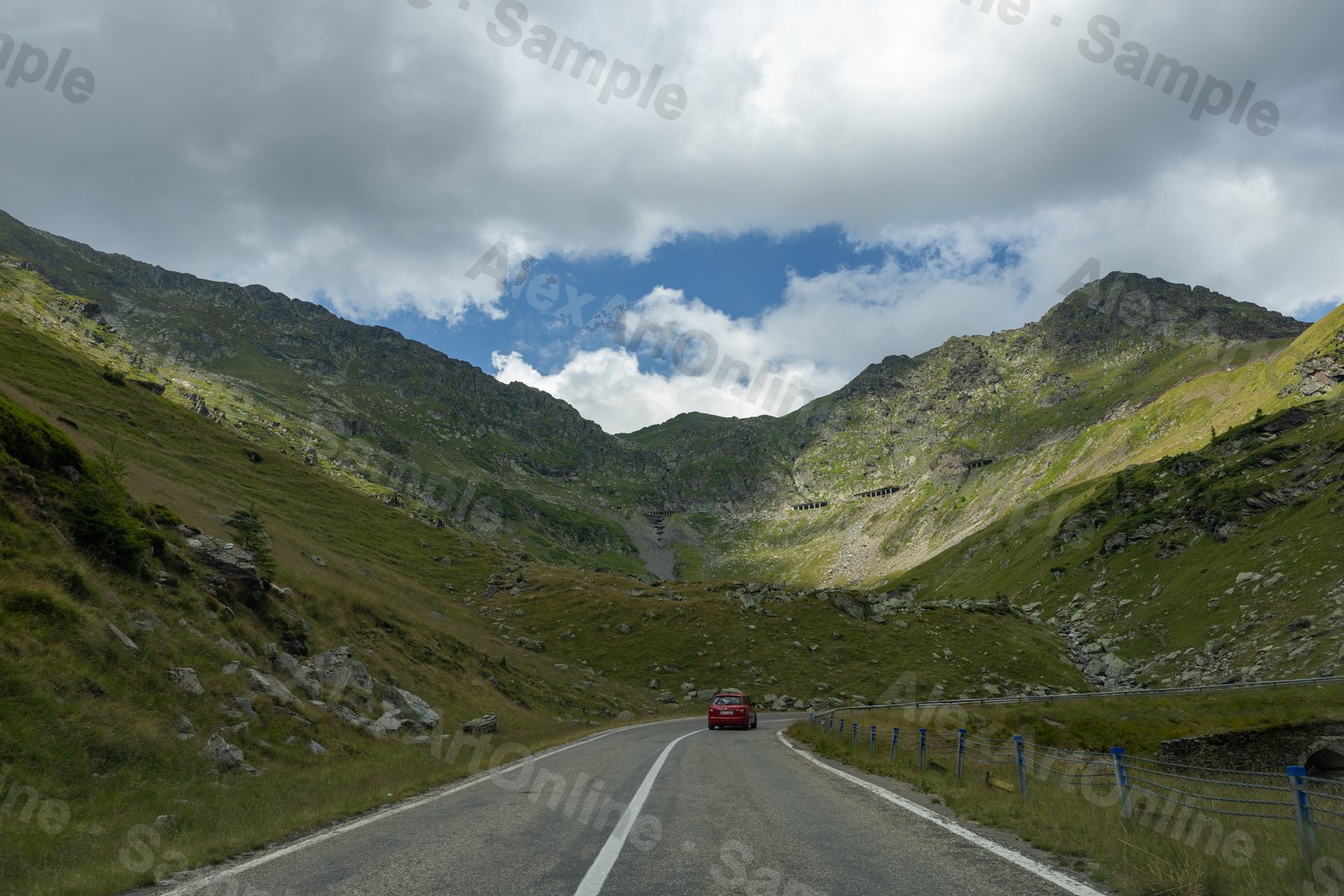 A car descending the Transfagarasan mountain road under a dramatic sky