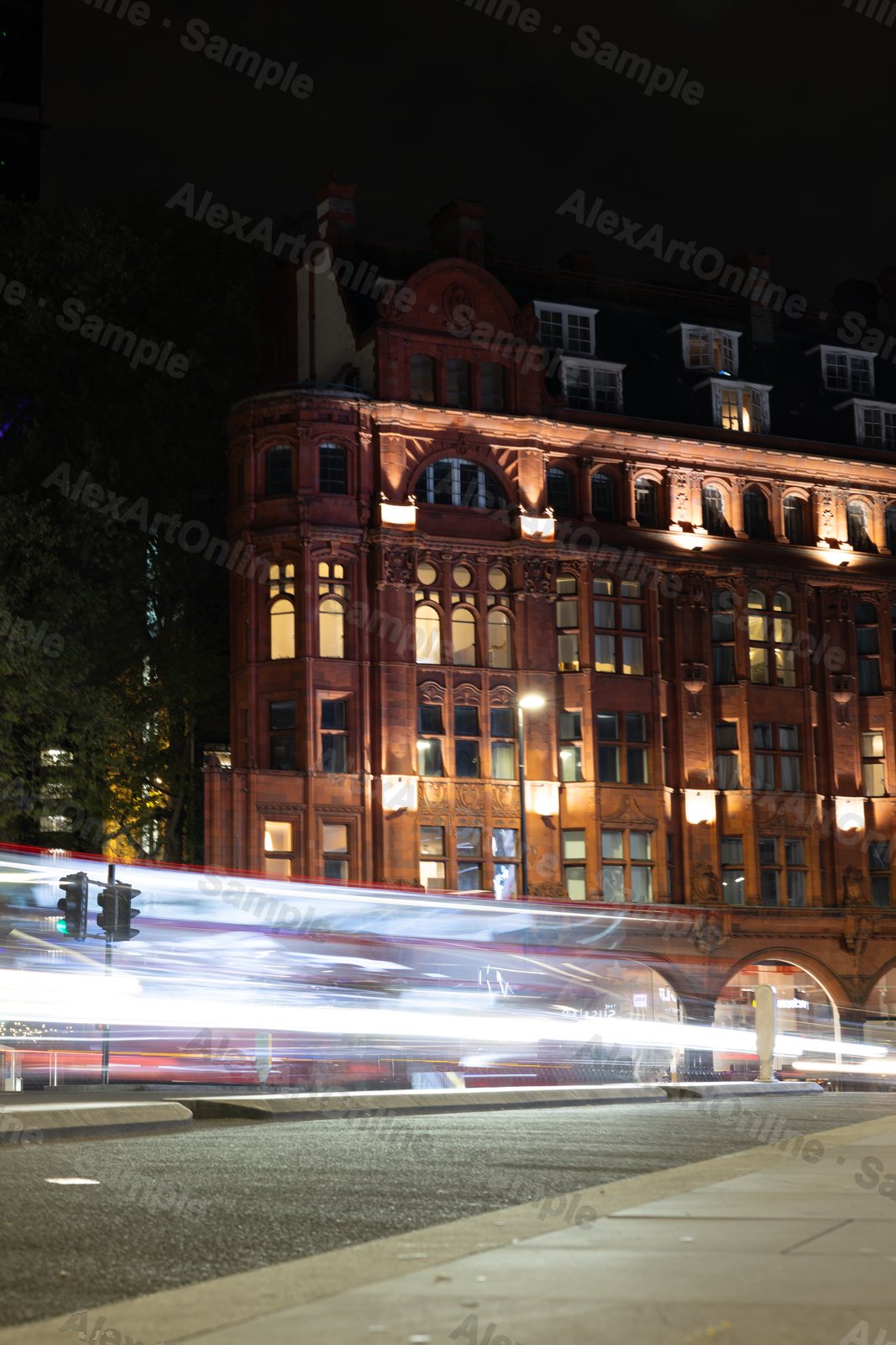 A red brick building lit up at night with light trails on the road